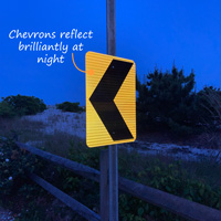 Road chevron sign reflects at night